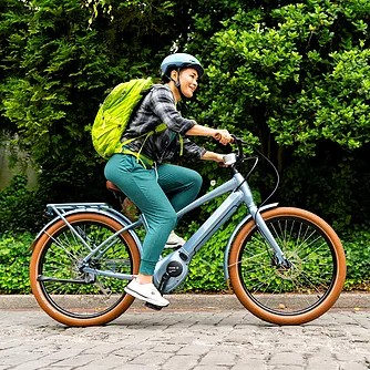 Person riding cruiser electric bike with backpack