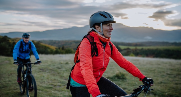 Man and woman e-bike riding with a mountain backdrop