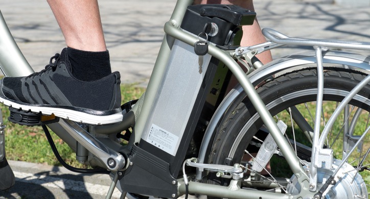 Cyclists legs with a closeup of the battery on an electric bike