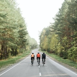 three bike riders cycling down a wooded road