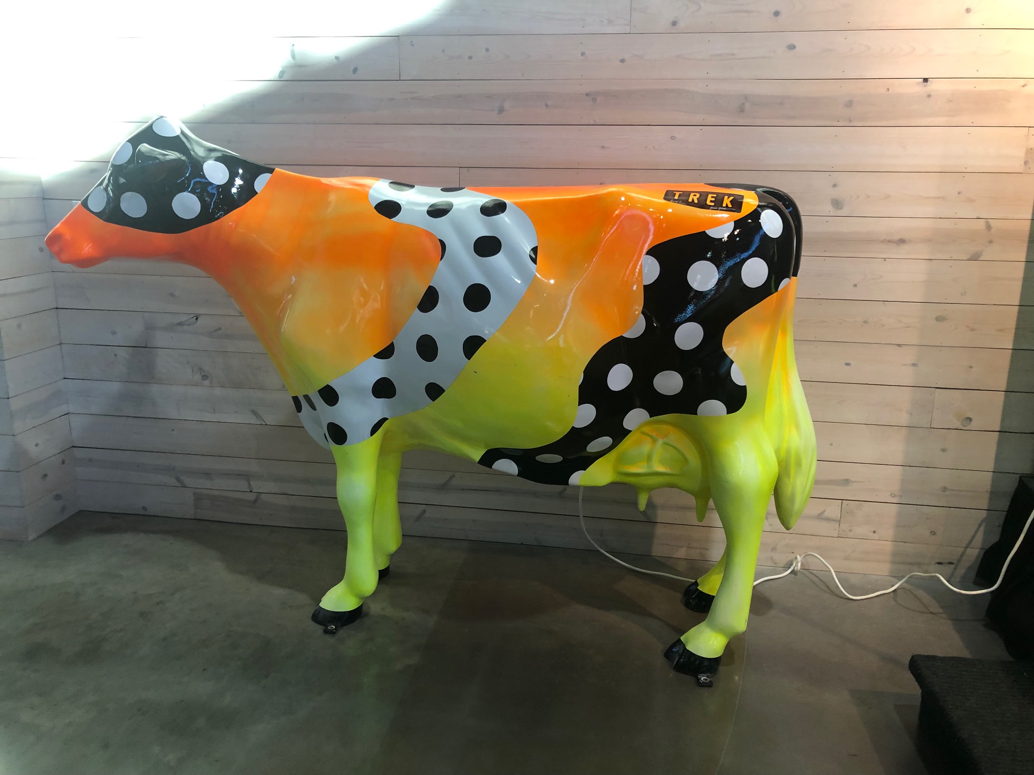 Cow figure that is very colorful. Orange to yellow fade from top to bottom with a black and white swirl with polka dots