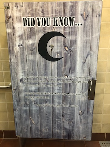Stall door with a fact "Did you know ...although now outhouses might seem nostalgic, they can be filled with flies and spread disease. Aren't you glad restrooms today are cleaner and more sanitary? They smell better too! Homestead National Historic Park uses only non toxic cleaners to keep these restrooms clean. What are you doing to promote "green" cleaning?"
