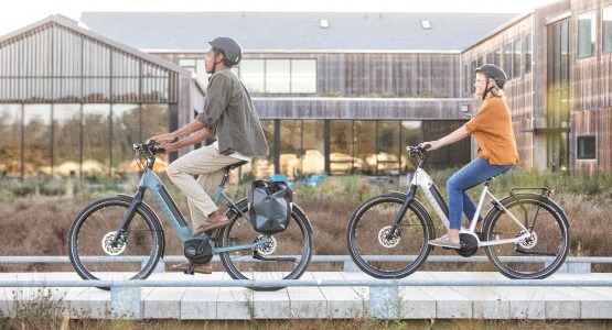 2 people riding electric bikes on a board walk