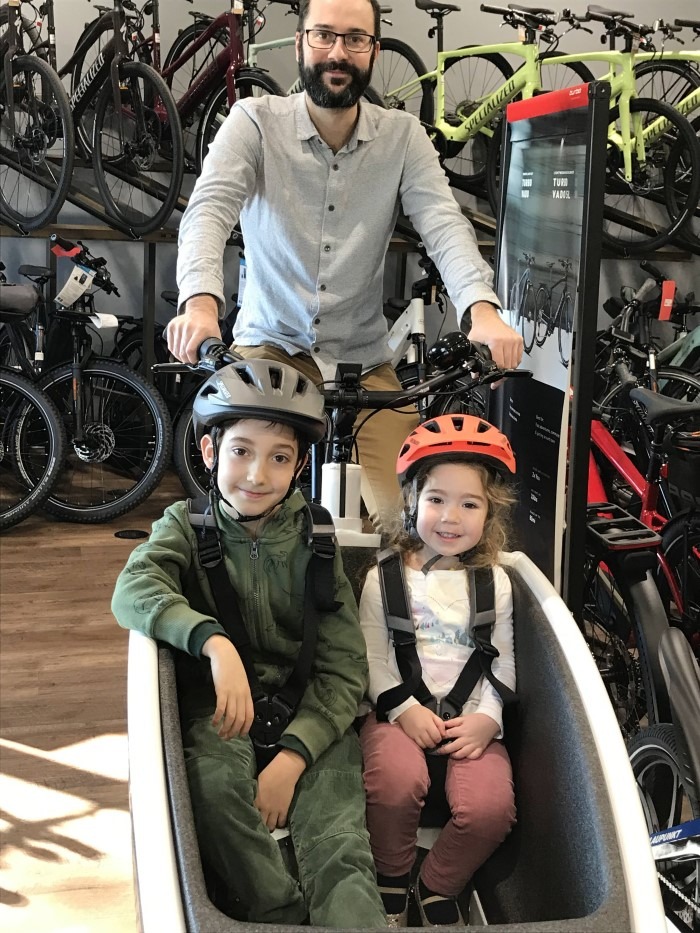 Dad and two kids in the Urban Arrow family cargo ebike in the store