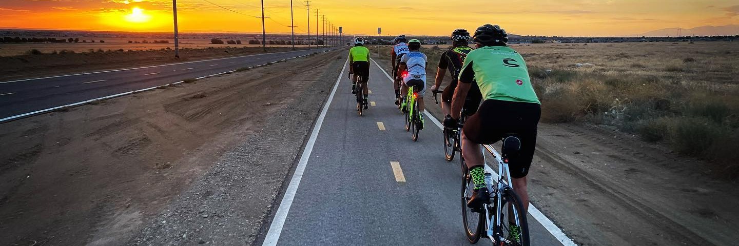 Five cyclists riding during a sunset.