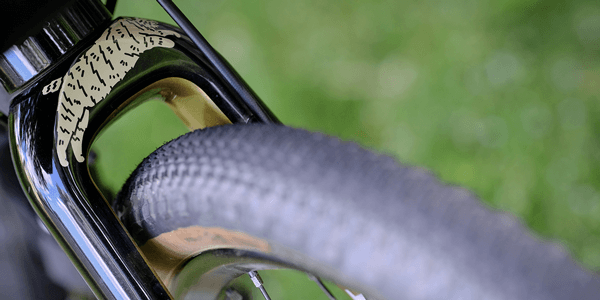 Closeup view of bike tire between a gloss black fork.
