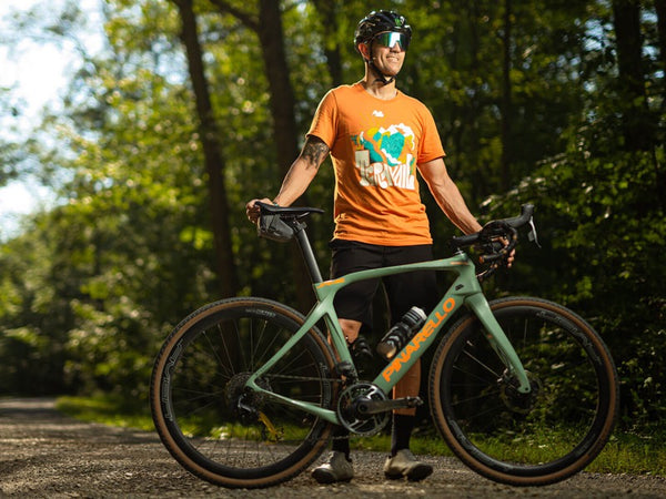 Jamie Bestwick standing with his gravel bike on a tree-lined trail