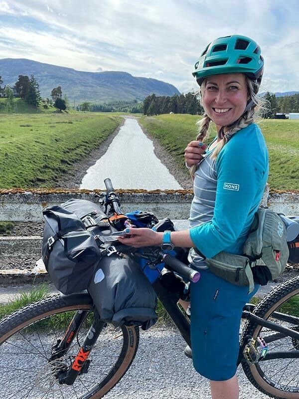 Kate poses with her bike loaded with gear on a bridge