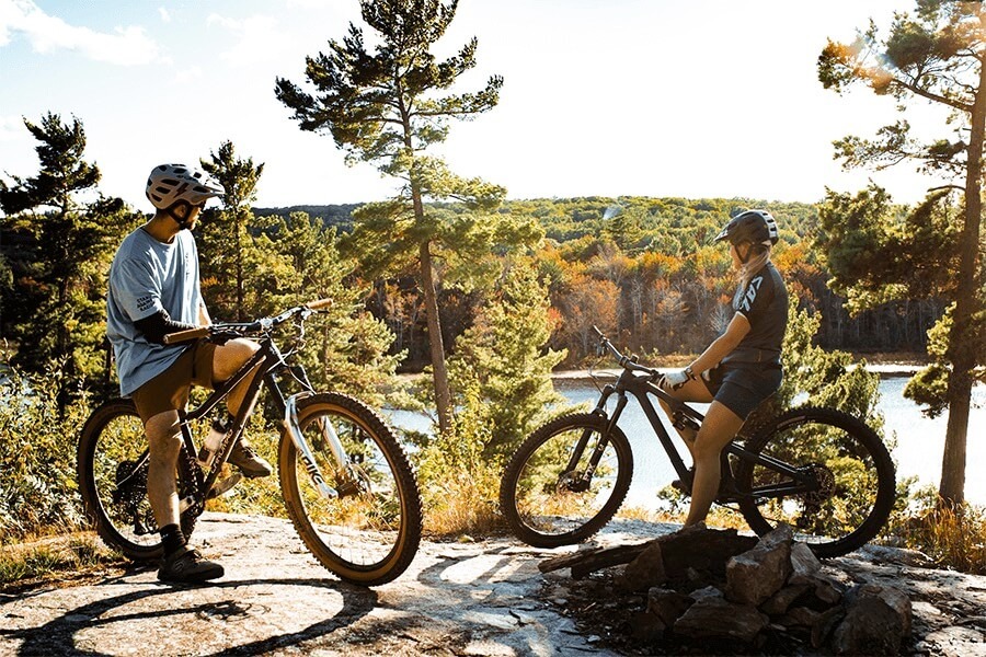 Two riders on their mountain bikes at a scenic overlook above a river