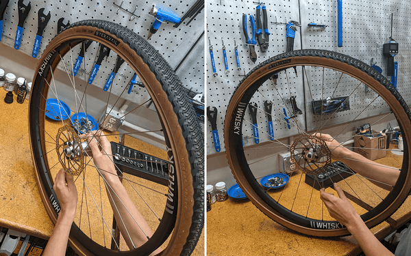 A bike wheel is being held over a shop bench with a Teravail tubeless tire being fit over the rim. by the hub.
