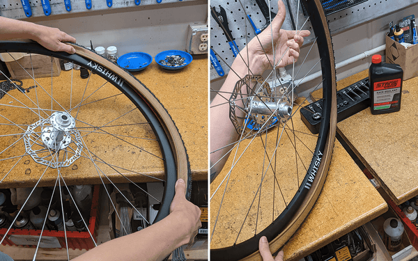 A Teravail tubeless tire is being pushed into a bike rim on a workbench.