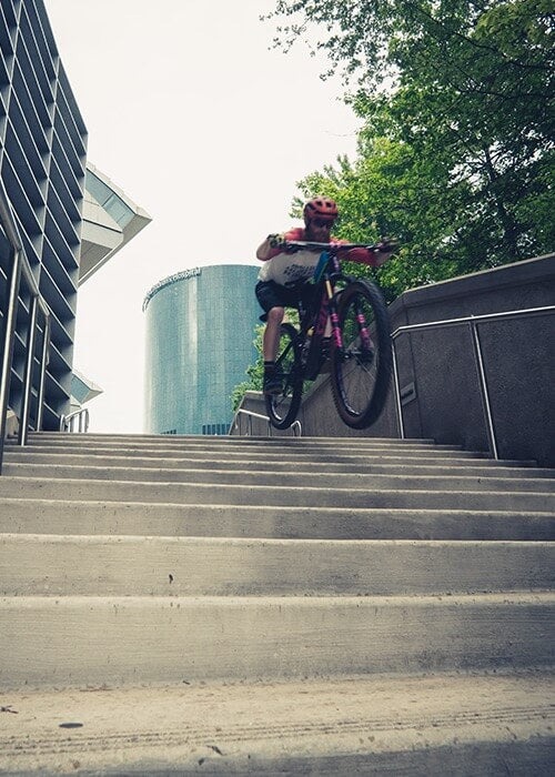 A mountain biker rides down a set of urban concrete stairs