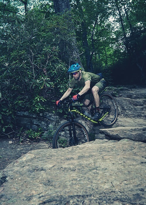 A mountain biker descends down a rocky trail on a full suspension bike