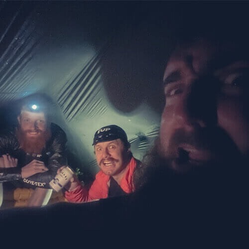 Three riders hangout together in a tent waiting out a storm