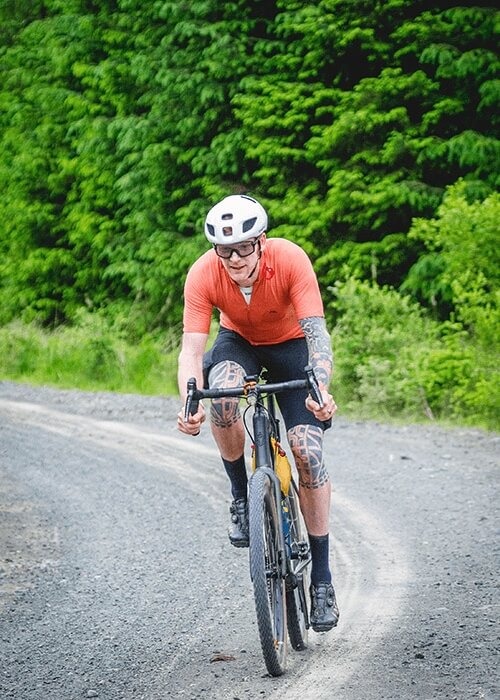 Steve Bate rides his bike down around a curve on a gravel road