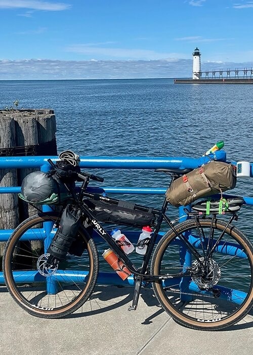 Adam's Surly bike is resting agains a railing overlooking water. It is packed with gear.
