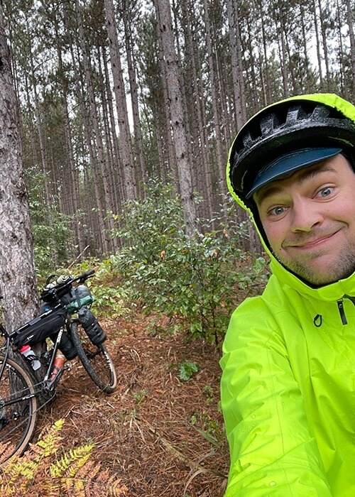 Adam takes a selfie on the forest trail while wearing rain gear