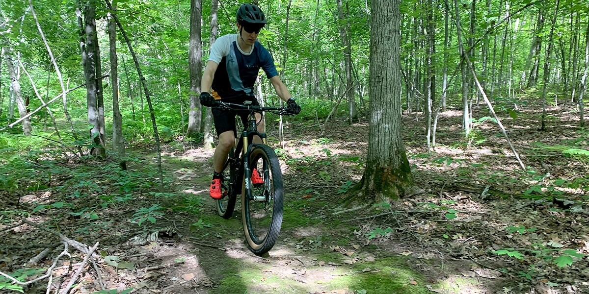 Paul is shown from the front riding along the narrow dirt trail on his mountain bike