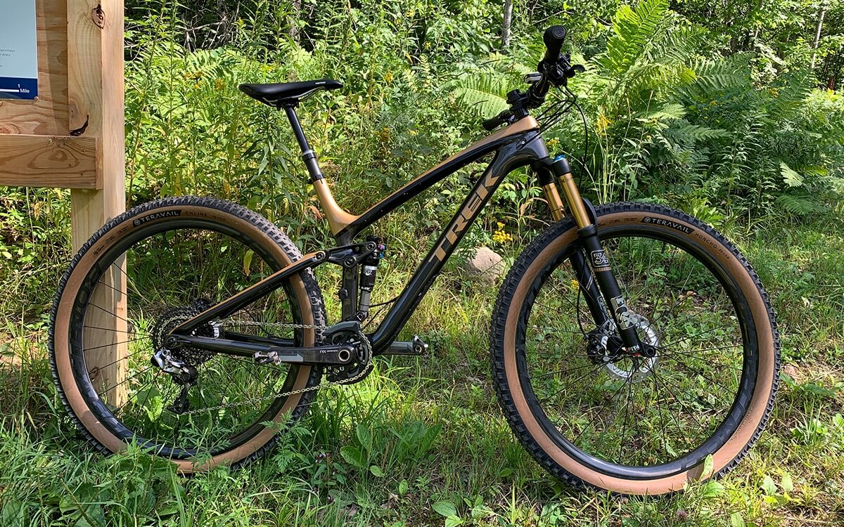 Paul's Trek mountain bike is propped up against a wooden trail sign at a mountain bike trail