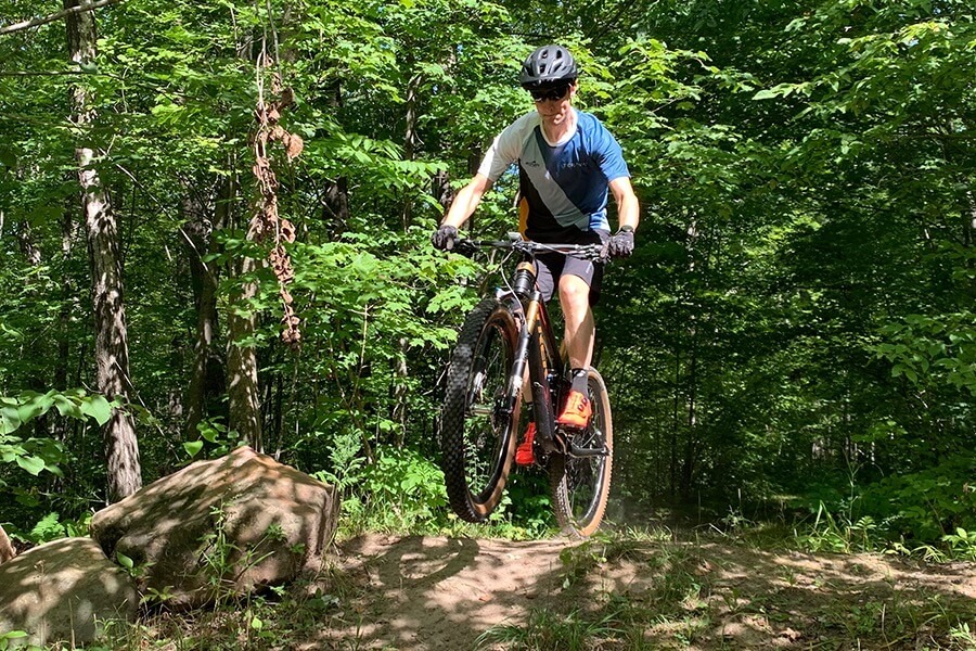 A cyclist gets some air while riding their mountain bike on a dirt trail