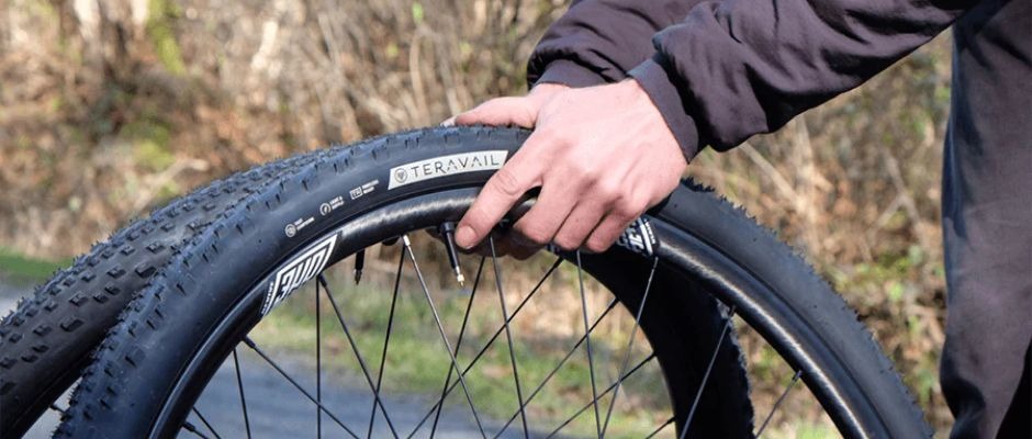 A rider's hands hold two bike wheels with Teravail tires mounted on the rims