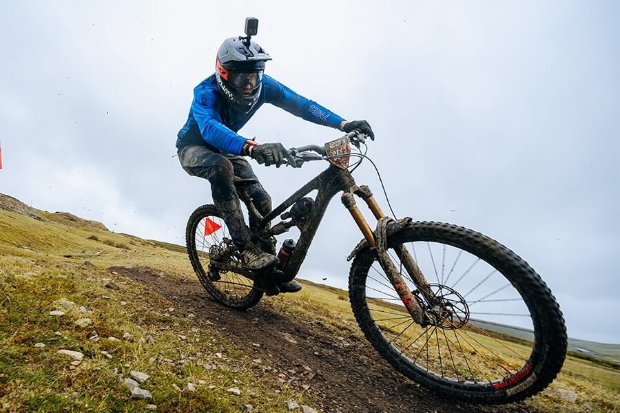 Mountain bike wearing a camera on his helmet aggressively descends downhill terrain.