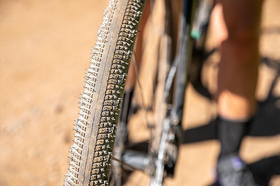 Closeup of a bike's front Washburn tire. The tread detail is visible and it's covered with red dirt.