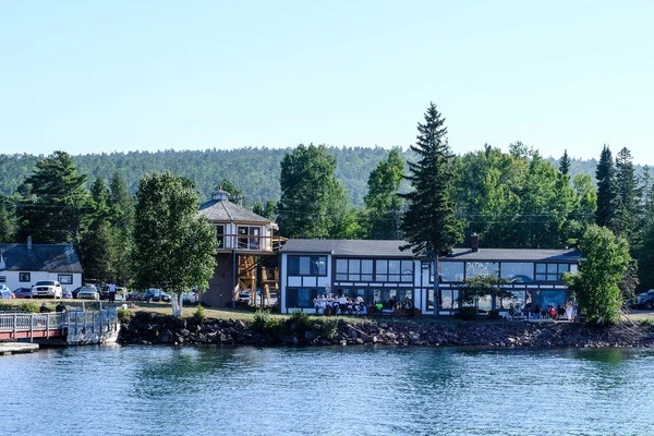 Buildings along the shoreline of the lake with tall trees in the background