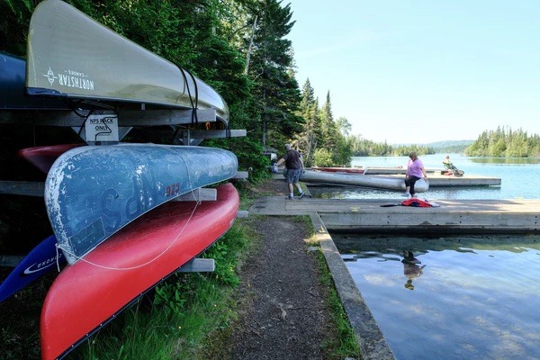 Canoes are lined up on racks at the edge of the lake