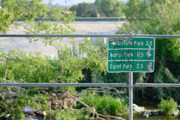 A city street sign in LA showing distances to Griffin Park, Marsh Park, and Egret Park