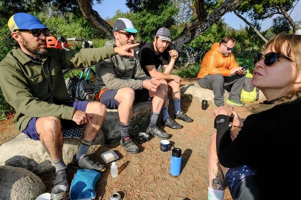 A group of cyclists sit and chat a camp site
