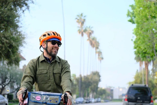 Cyclist smiles while riding down a street in LA