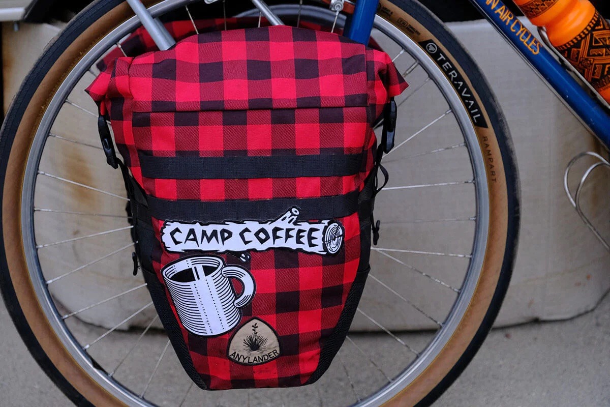 Closeup of bike with a pack over the front wheel with a Camp Coffee patch