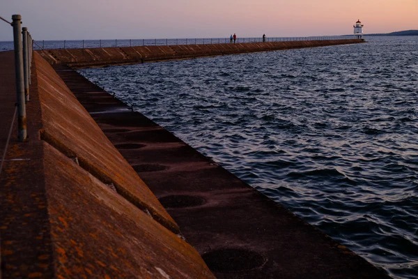 A long pier stretches into Lake Superior at sunset