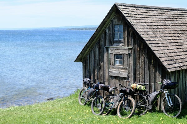 A small rustic building sits next to the lake. Bikes lean up against it.