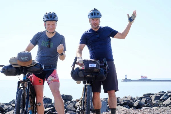 Two cyclists stand with their loaded bikes and pose for the camera