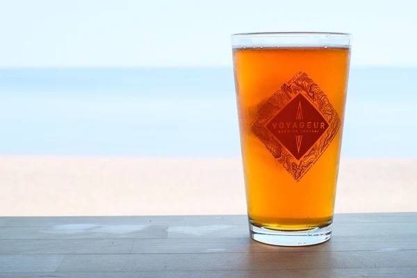 Pint glass sits on a bar in front of the beach and lake
