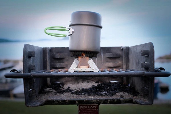 A camp stove being used on a park grill