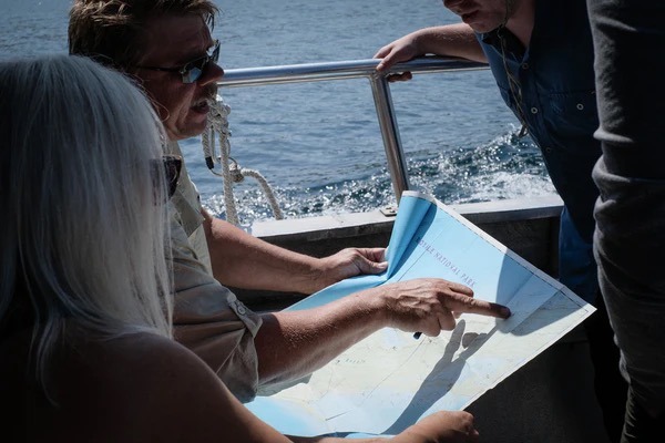 A few people look at a map while on the boat