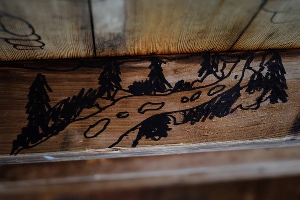 A drawing of a tree lined path drawn in marker on wood