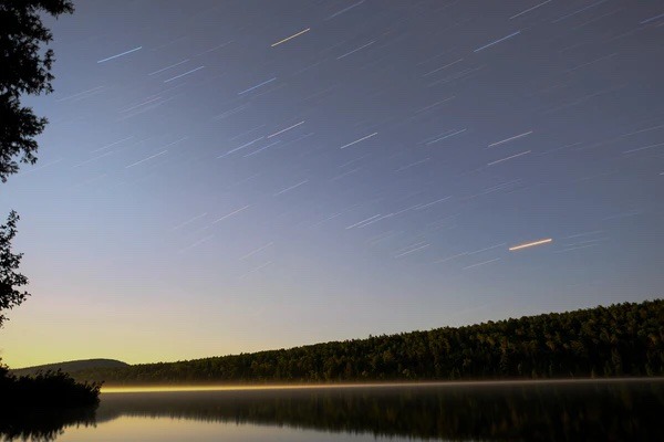 Shooting stars fly over the lake at night