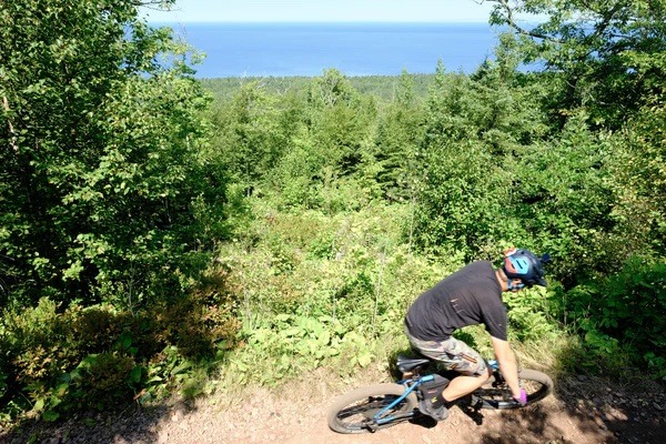 Mountain biker shown from above rides on a trail along the lake