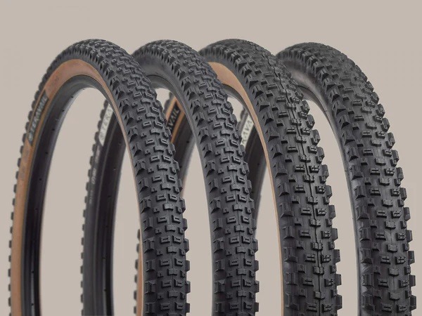 A lineup of Honcho tires against a tan background with tread detail visible