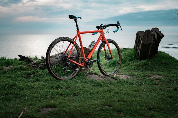 Gravel bike with Rutland tires is shown on a cliff with a large lake in the back.