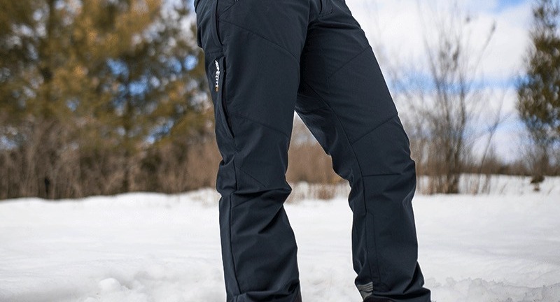 A cyclist stands in deep snow while wearing 45NRTH winter cycling pants in the women's cut.