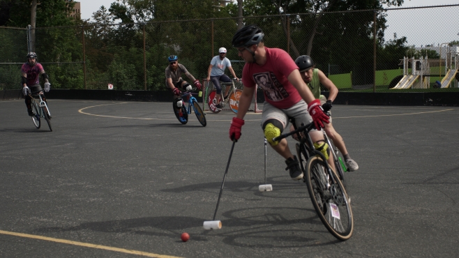 Two bike polo players in a fierce chase for the ball at EV Tremblay Park