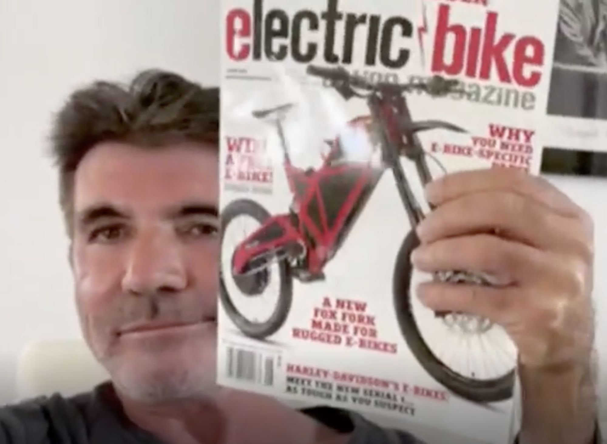 Simon Cowell holding up a magazine with his near-death-causing motorized bike on the cover.