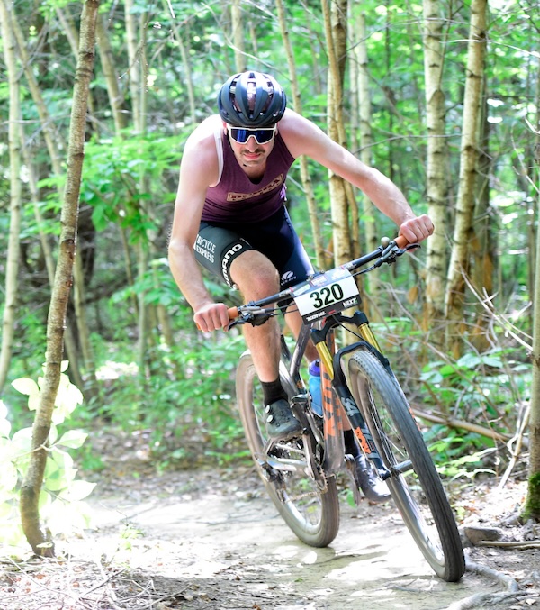Matt Green riding a mountain bike on a trail with trees on both sides