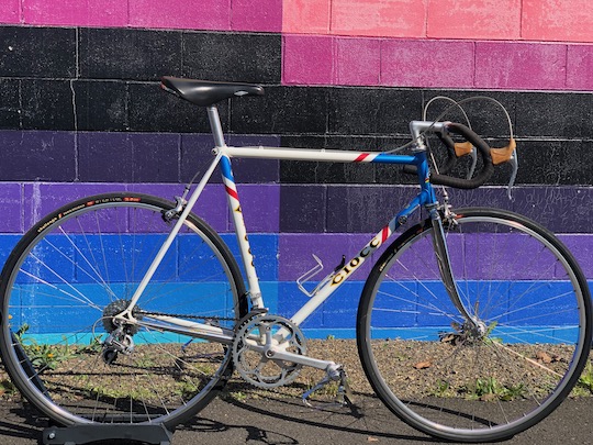 A side view of a classic, steel frame Italian Ciocc road bike that is painted red, white, and blue. It has a Shimano 600 groupset.