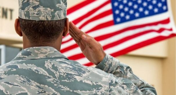 Military person saluting the US flag